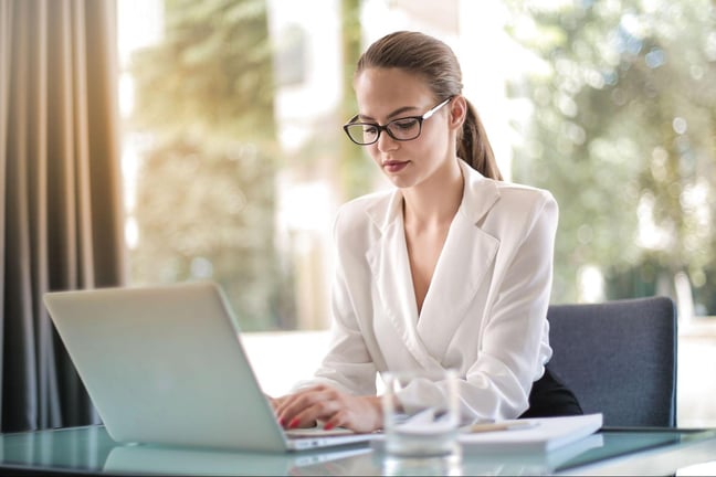 Business professional working on laptop using compliance management software