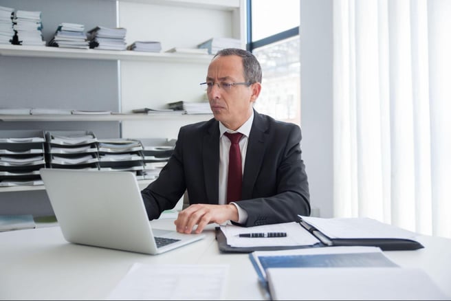 Executive reviewing financial records on laptop with compliance management software