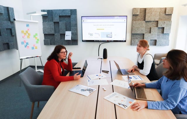 Finance team reviewing reports on-screen and in print, discussing compliance management software adoption