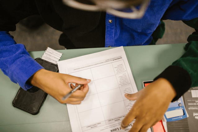Person completing a training quiz or survey on paper at a desk as part of their compliance training.