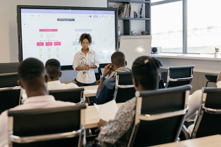 Instructor leading a workplace compliance training session with employees in a modern classroom setting.