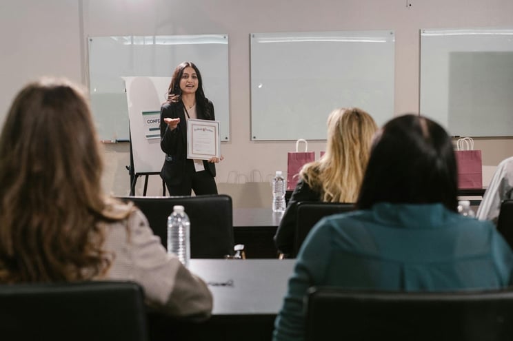 Businesswoman holding a certificate and speaking to an audience during a professional training or corporate workshop.