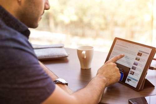 Professional reviewing compliance training on a tablet with an LMS for manufacturing industry solution to streamline audits and training completion.