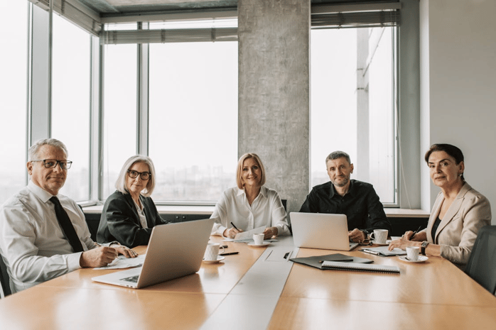 A happy pharmaceutical team sitting together in a meeting, discussing compliance strategies and reviewing documents in a modern office setting.